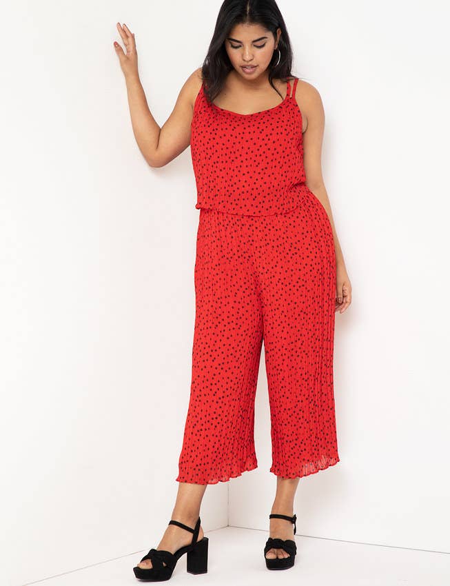 A model wearing a red jumpsuit with black tiny polka dots