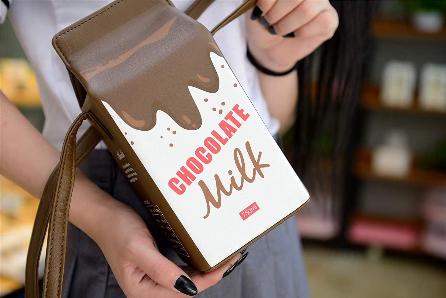 A person holding a chocolate milk handbag in a store