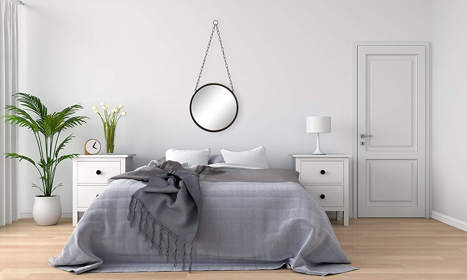 A round mirror with a chain hangs above a bed in a bedroom