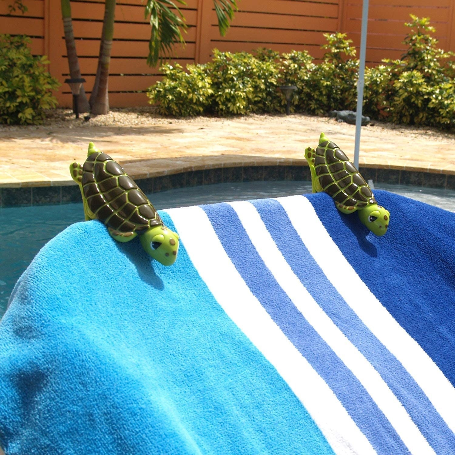Two turtle clips being used to clip a towel onto a chair