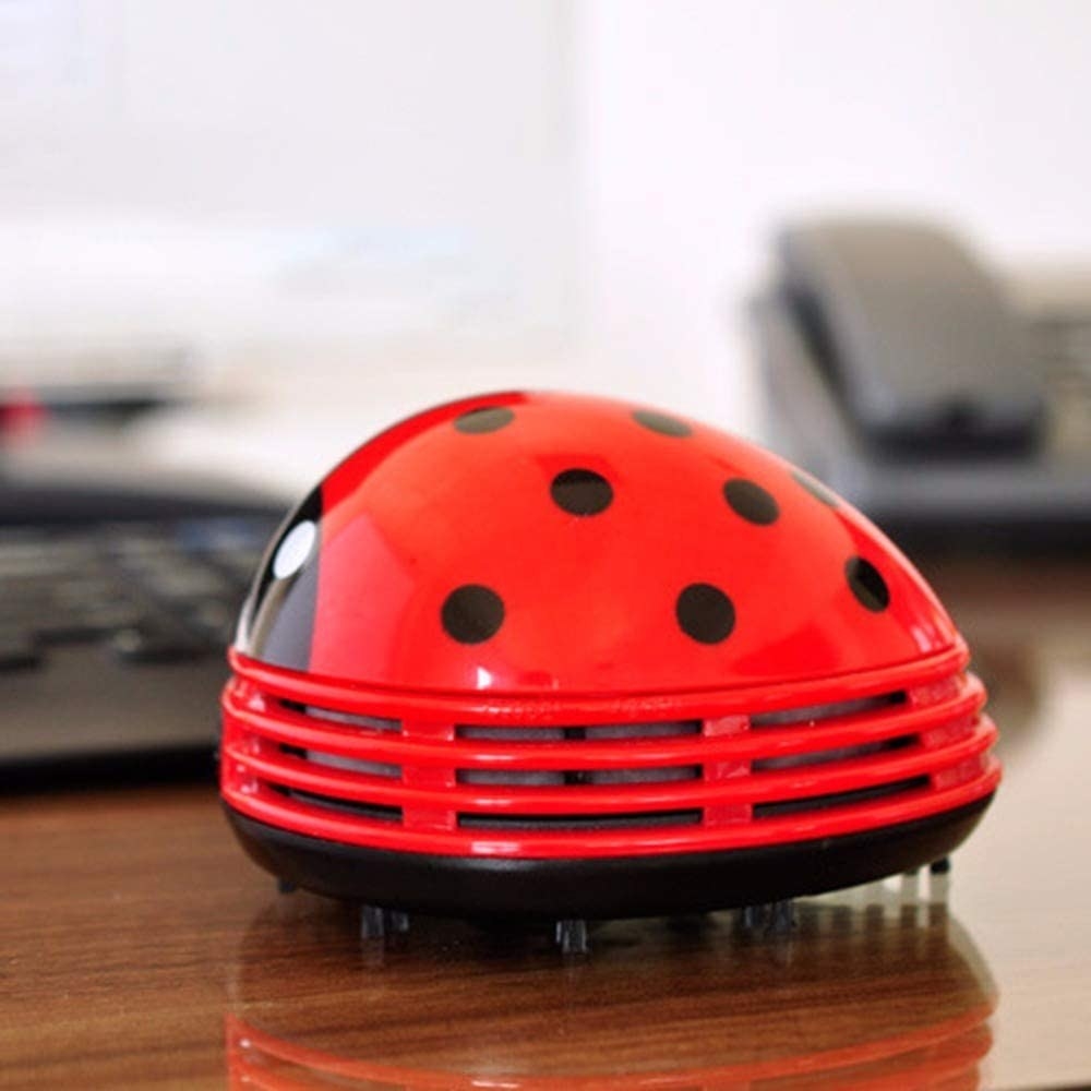 The ladybug vaccum sitting on a desk in front of a computer keyboard