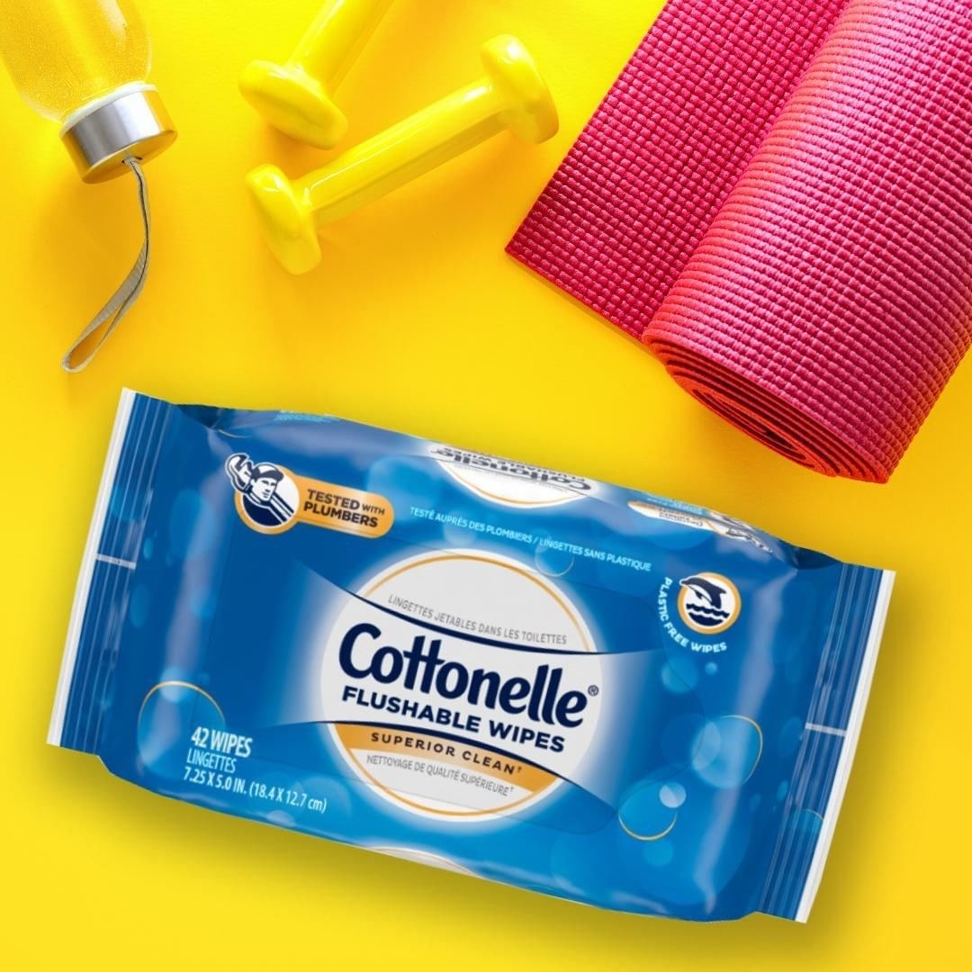 A pack of wipes is on a yellow background with a yoga mat, dumbbells and a water bottle