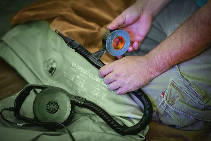 A person uses a roll of gorilla tape to seal an air pump hose