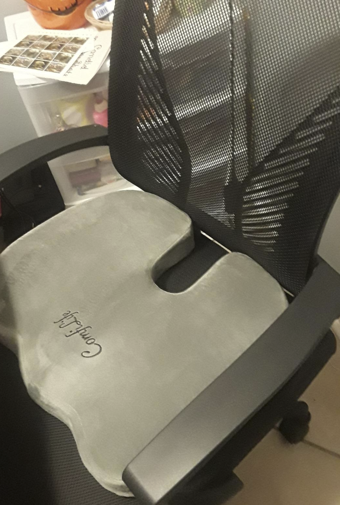 The gray cushion in an office chair. It has a slightly rectangular shape with rounded edges and an empty space near the tailbone to relieve pressure