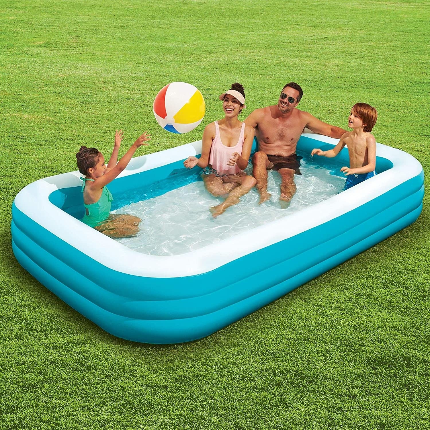 A family of four plays with a ball inside the pool