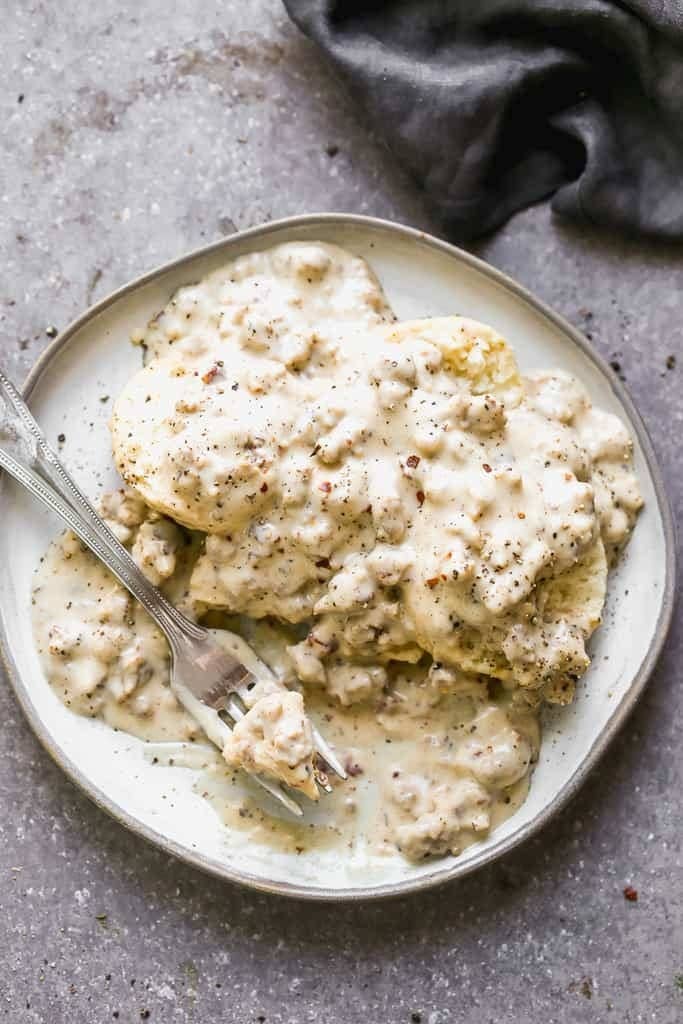A plate of fluffy biscuits smothered in a creamy sausage gravy