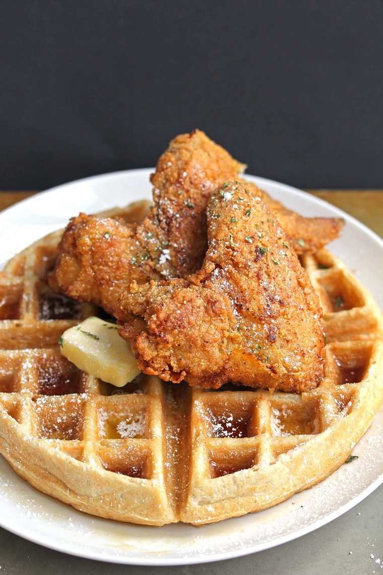A big, round, golden waffle topped with a knob of butter and two pieces of crunchy fried chicken