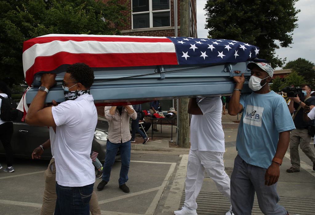 Protestors carry an empty coffin draped with an American flag