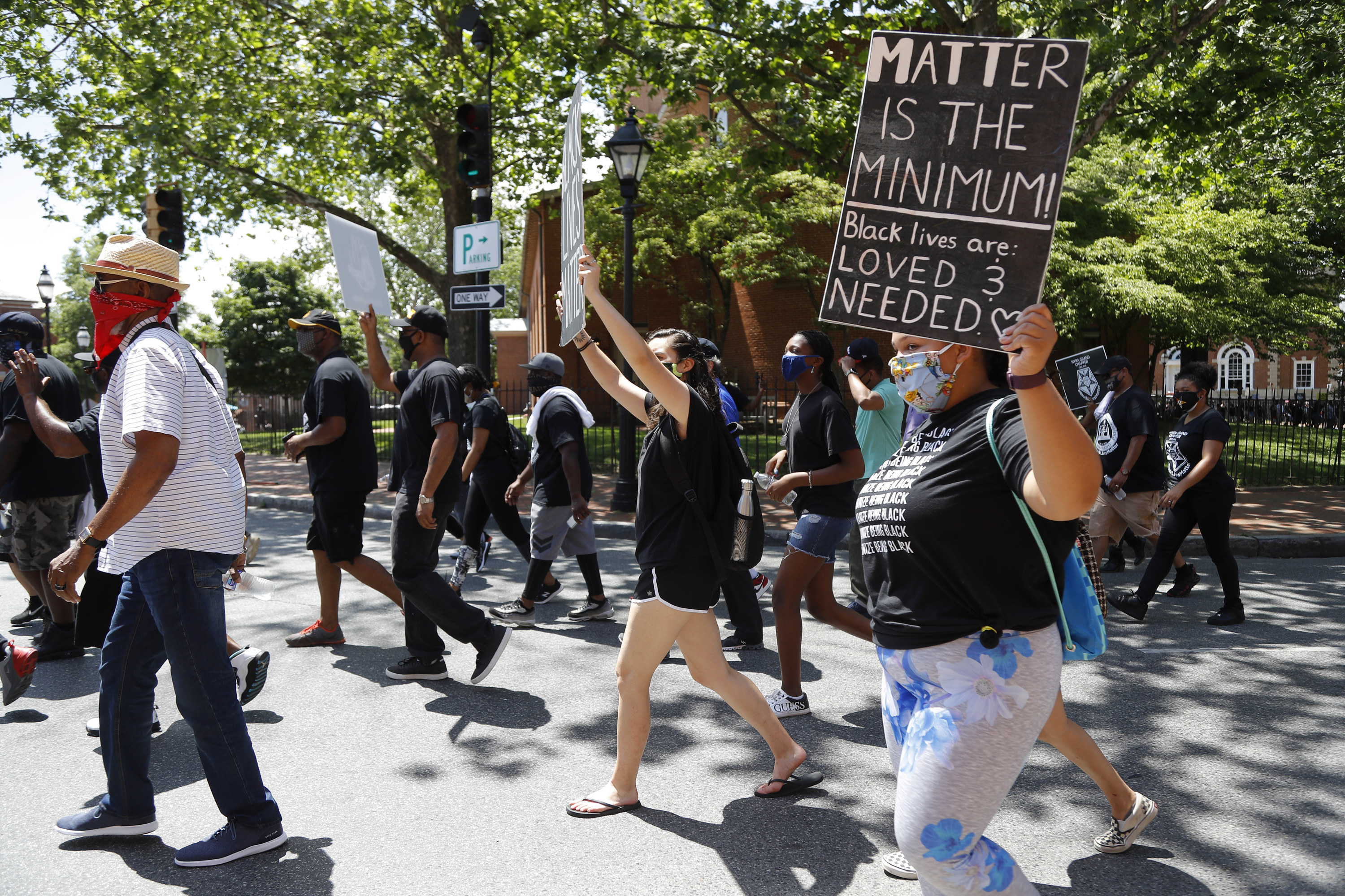 People hold signs while marching. One person&#x27;s sign reads, &quot;Matter is the minimum! Black Lives are loved and needed&quot;