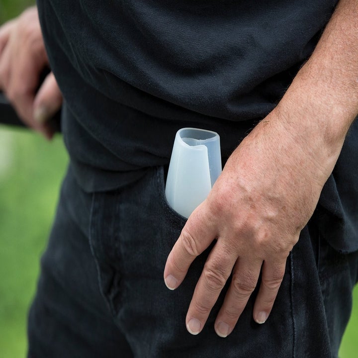 The silicone wine glass folded securely in  a person's pant pocket.