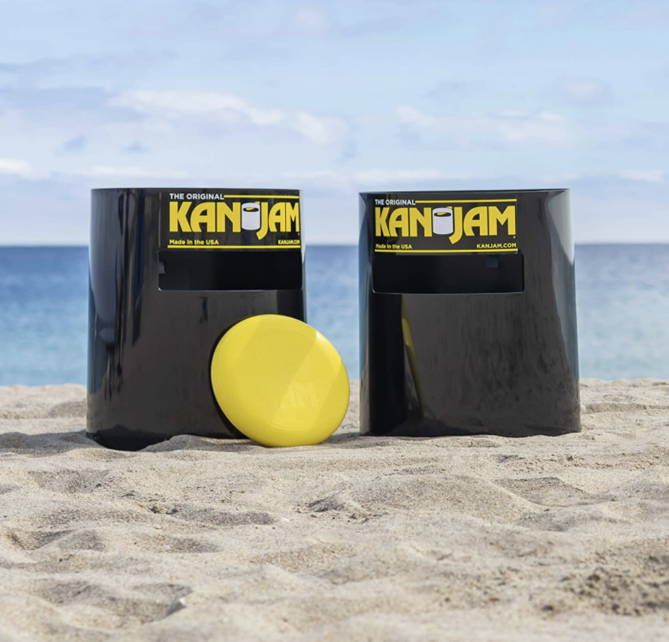 Two Kan Jam cans and a yellow frisbee on a beach