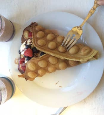 An egg waffle wrapped around ice cream and fruit 