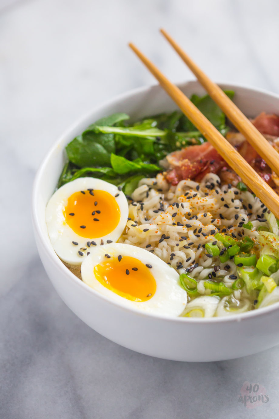 A bowl of ramen noodle soup with scallions, bacon, and soft boiled egg.
