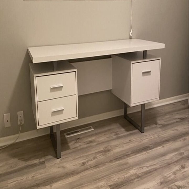 An empty white writing desk with two drawers on the left and one on the right