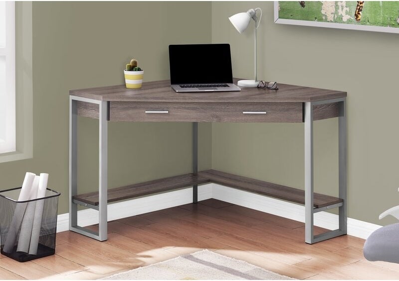 A birch color corner desk with metal legs and a center drawer