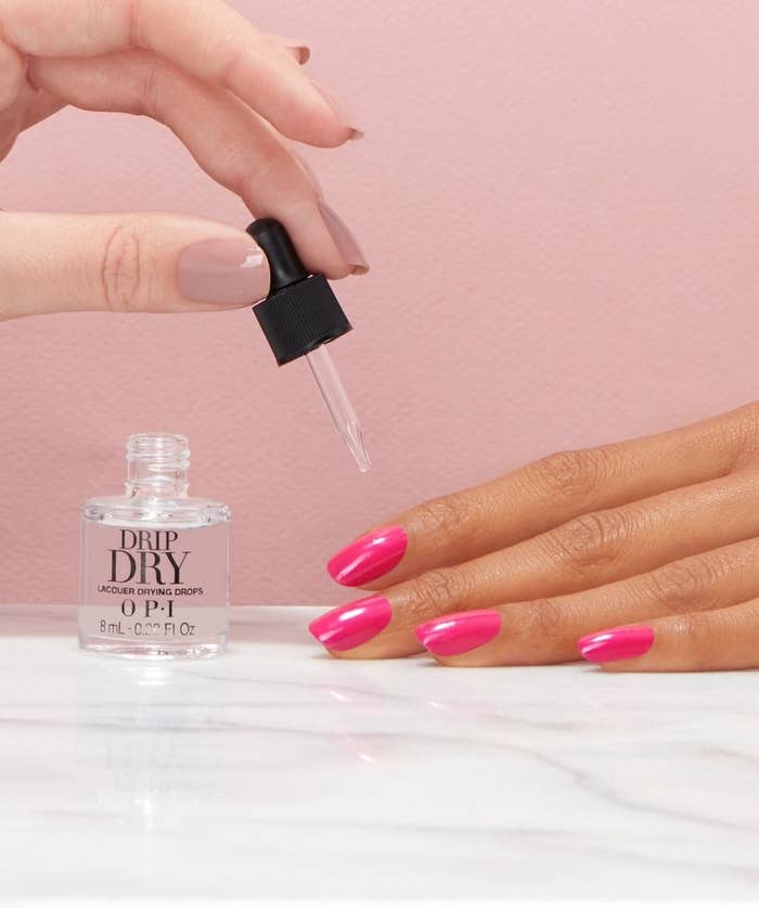 A person putting nail polish drops on their finished manicure