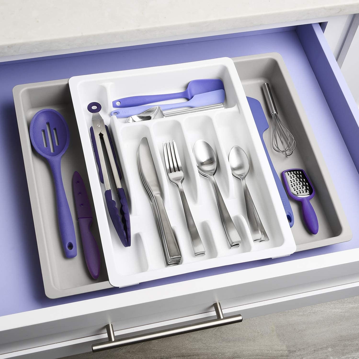 An expandable utensil tray in a drawer with utensils inside