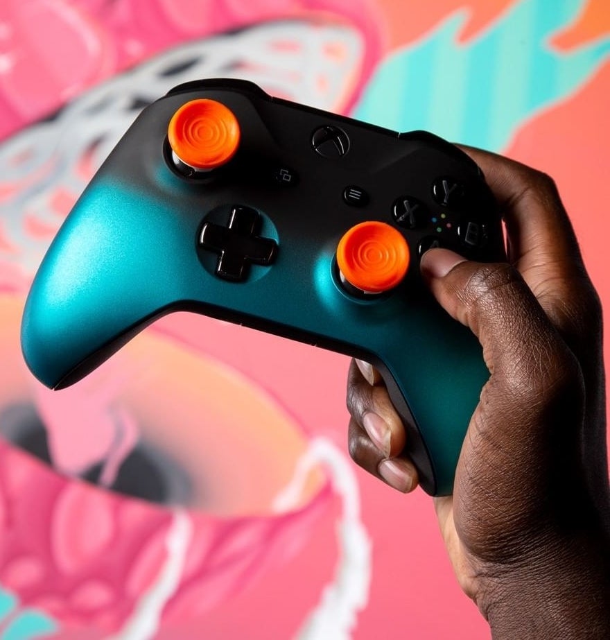 A person holding up a PlayStation 4 controller with performance thumbsticks