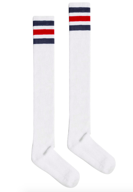 A pair of long slim socks are laid flat on a plain background
