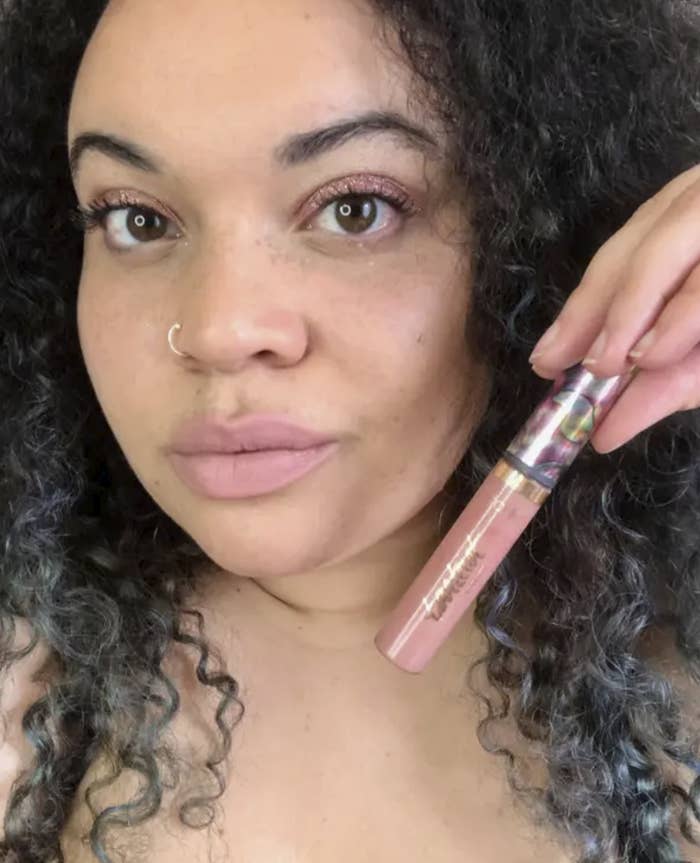 BuzzFeed editor Kayla Boyd holding wearing a nude pink lipstick and holding the tube near her face