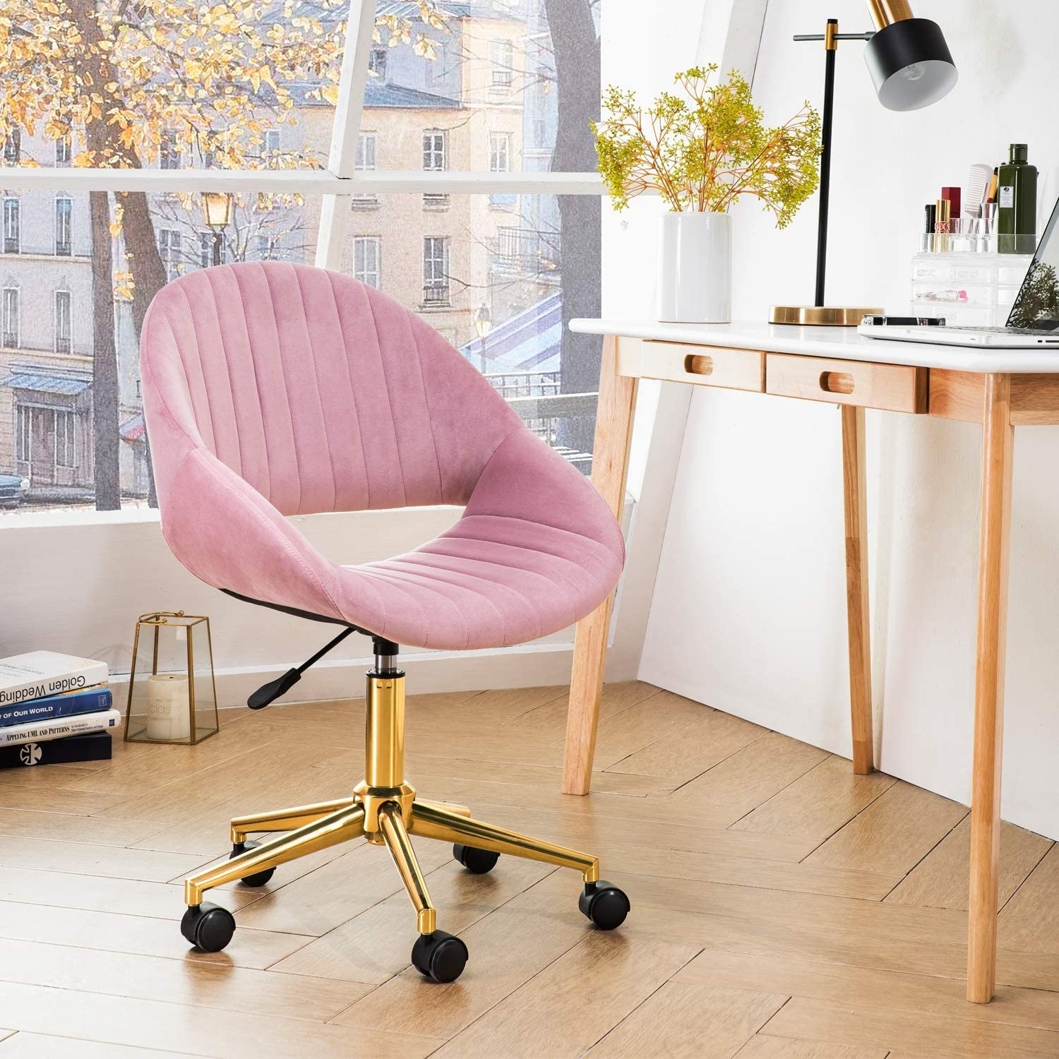 mid-century modern pink velvet rolling desk chair with gold tone base in a home office with a desk