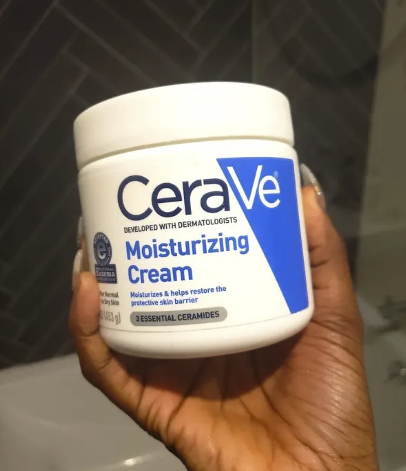 A person holding the tub of moisturizer