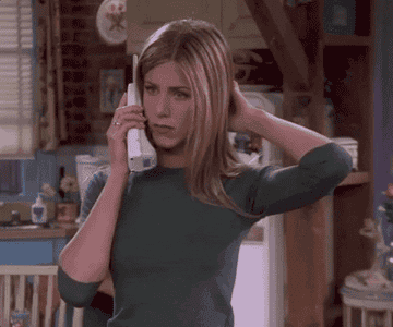 Gif of Jennifer Aniston from the TV show &quot;Friends&quot; on the phone and putting her hand over her mouth and to her head in shock