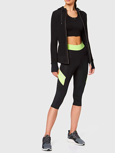 Model wears reflective workout capris with a zip-up hoodie and sneakers