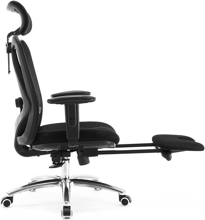 profile view of black office chair with head rest, foot rest, arm rests, silver hardware