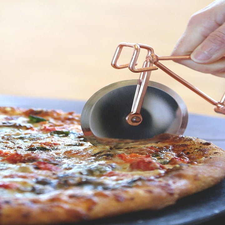 the pizza cutter cutting into a pizza