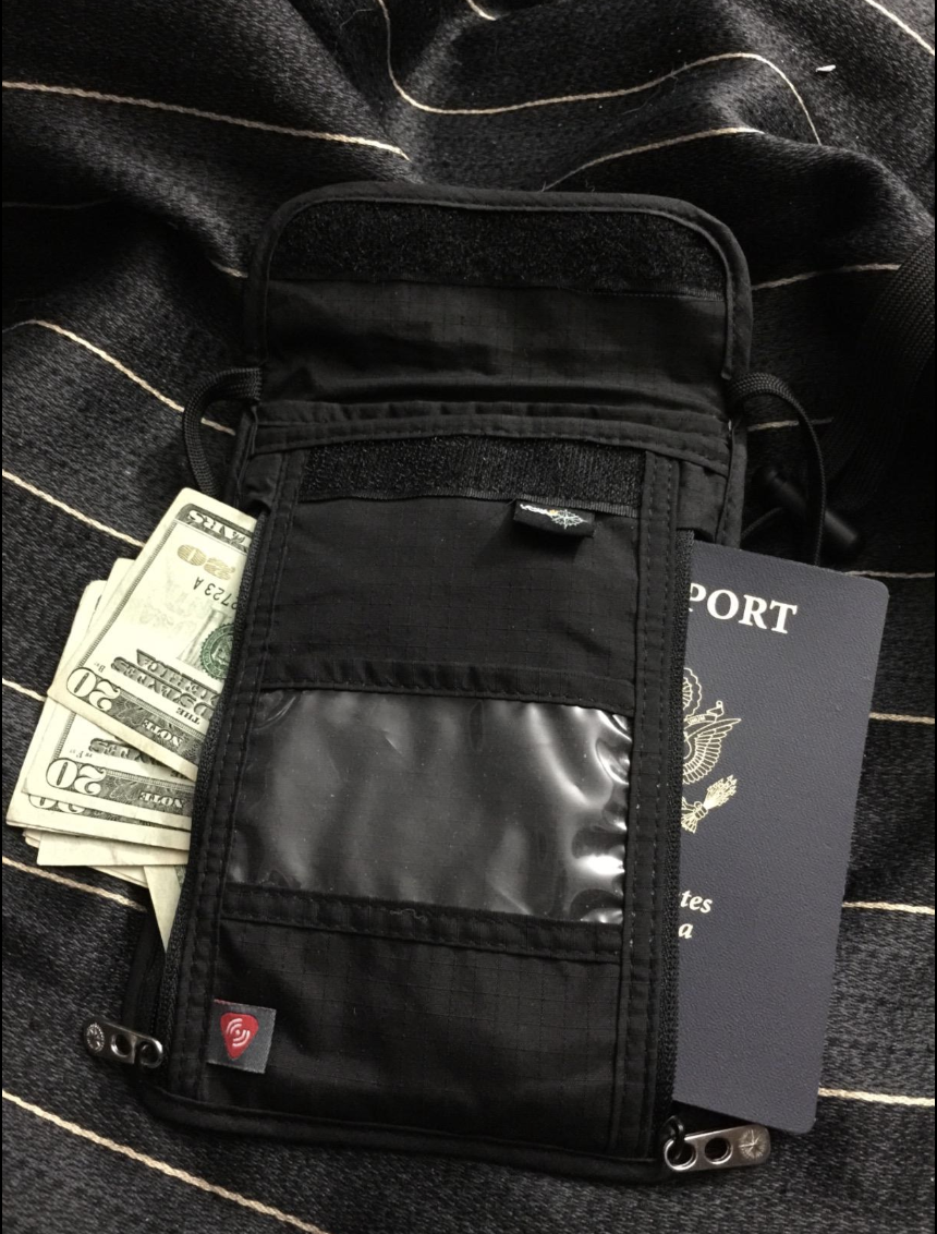 A reviewer image of the rectangular velcro pouch with a passport and money in it 
