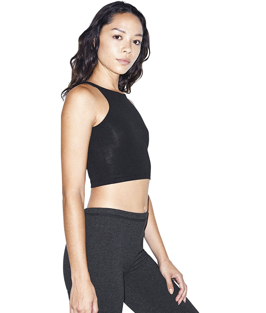 A model in a black compressive crop top that falls between the rib cage and belly button