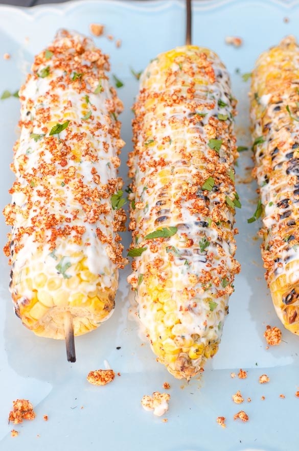 Three ears of Mexican street corn coated in a creamy mayo mixture and a Cotijia cheese and paprika crumble.