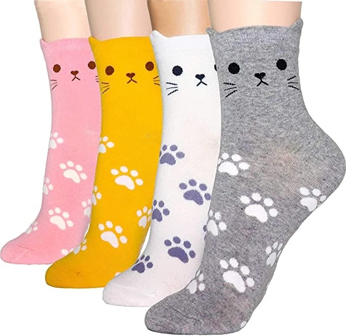 four feet with cat socks in pink, yellow, white, and grey