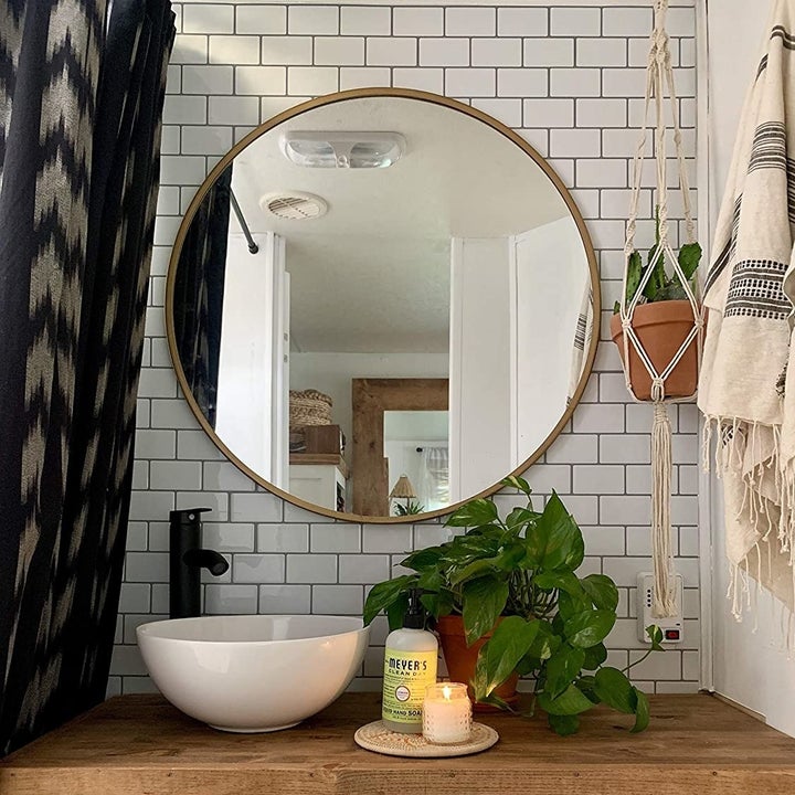 The tiles are the backdrop in a bathroom with a large round mirror and lots of plants