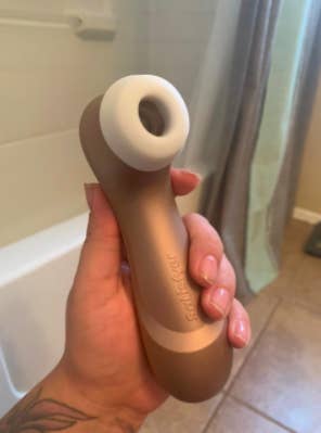 reviewer holding the sex toy with an O-shape opening for the sucking vibrations emit from