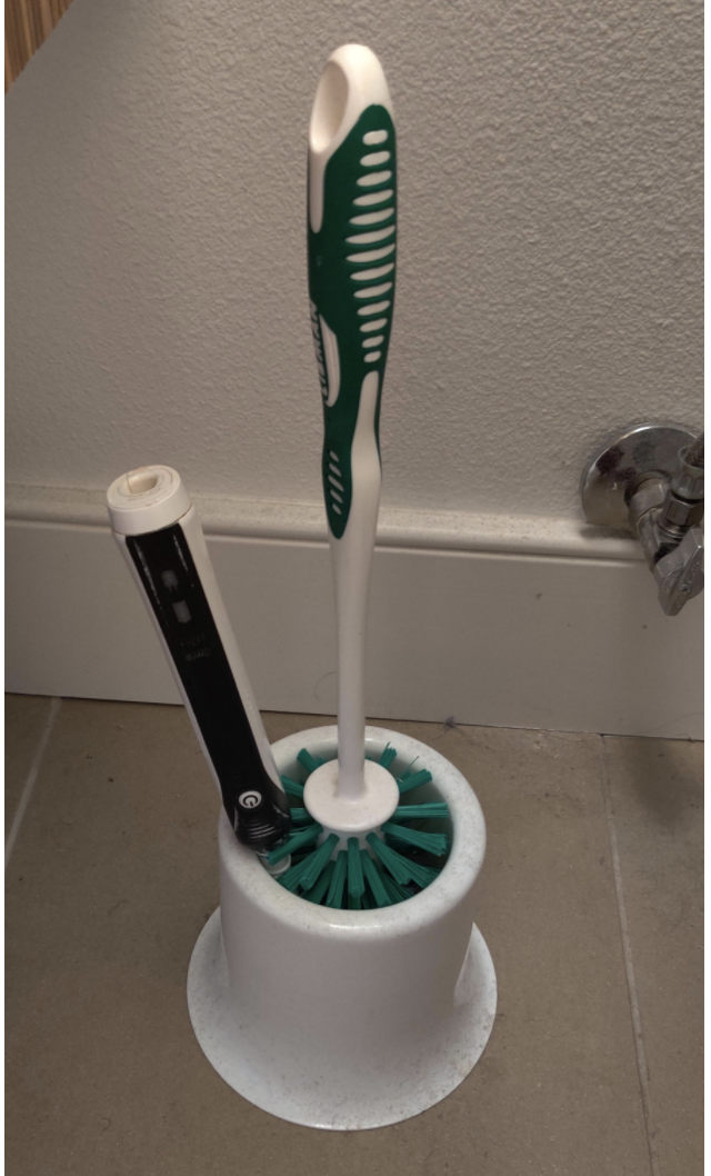 A phone stuck in the toilet brush holder