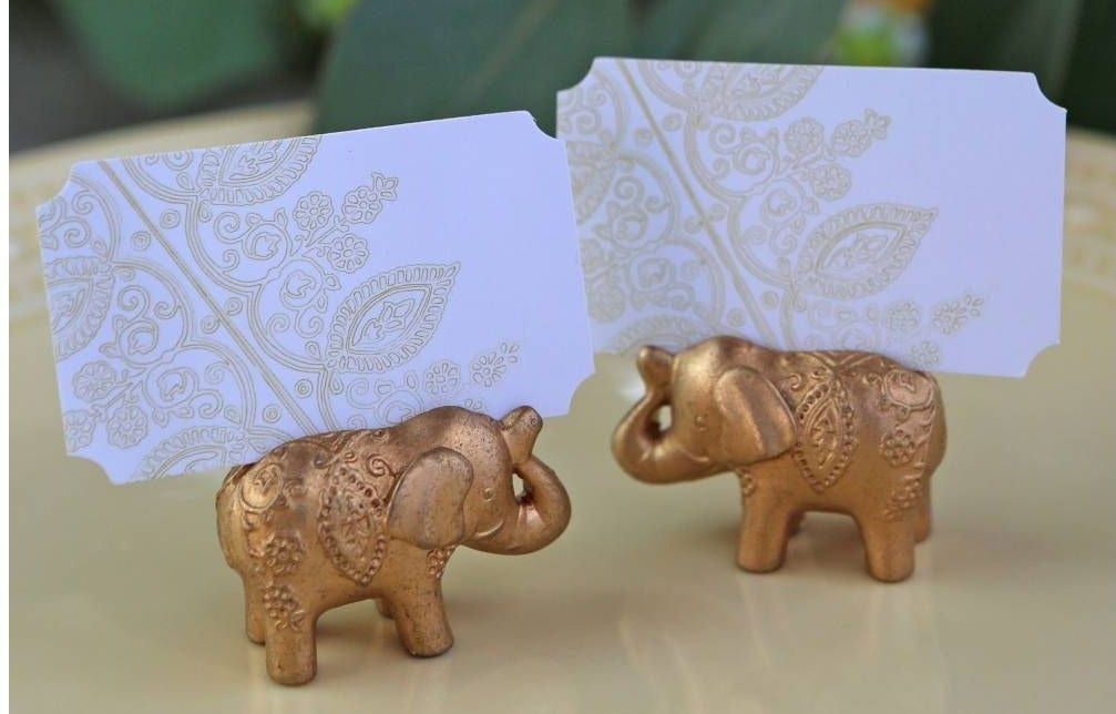 Two ornate golden elephants holding place cards