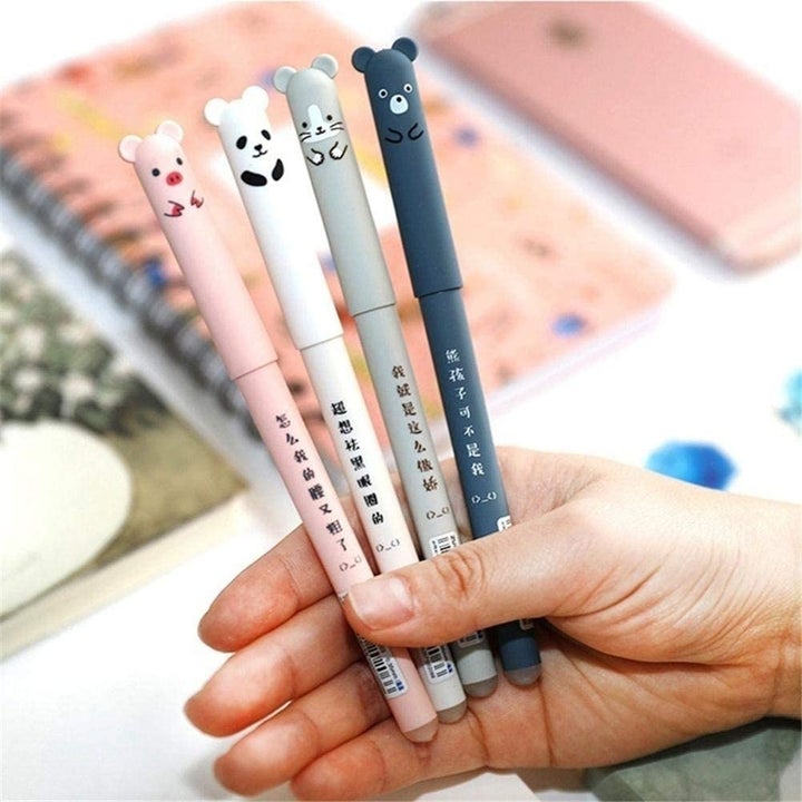 A person holding for gel pens with little animal faces on the lids