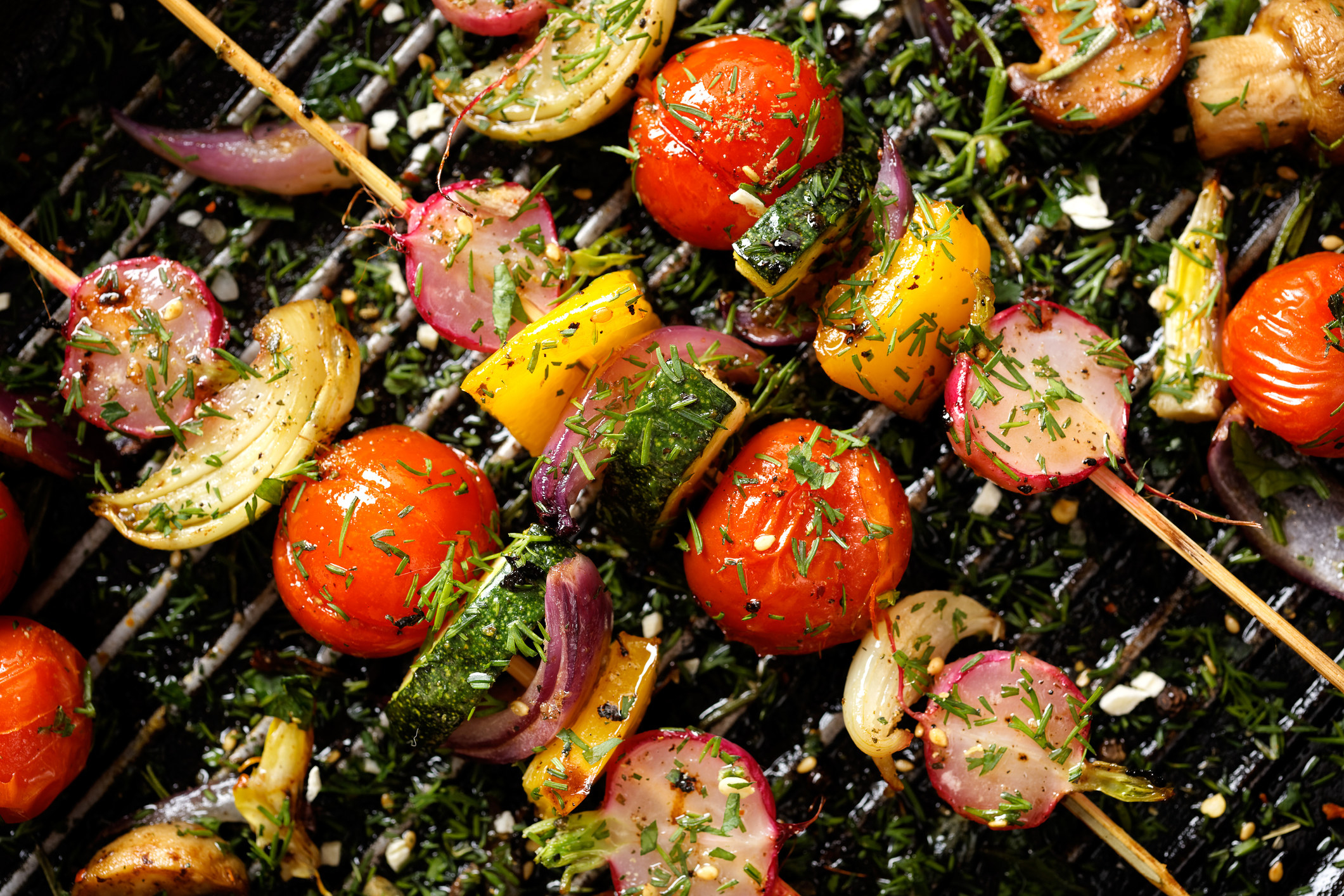 Vegetable skewers with tomato, onion, zucchini, and pepper on the grill.