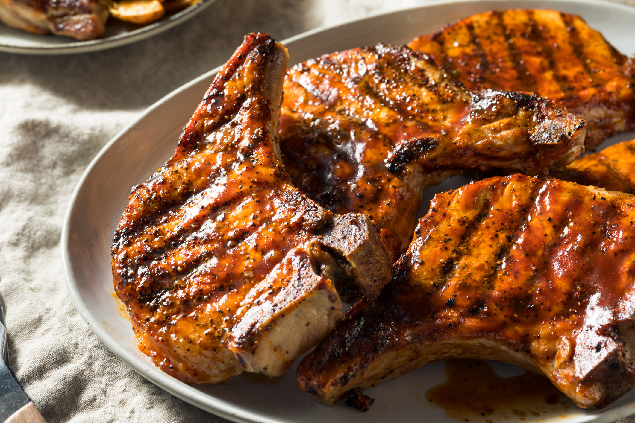 A plate of grilled bone-in pork chops with barbecue sauce.