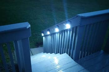 The lights mounted to the side of reviewer's porch steps and illuminating the stairs
