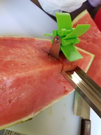 A reviewer cutting into a watermelon with the utensil