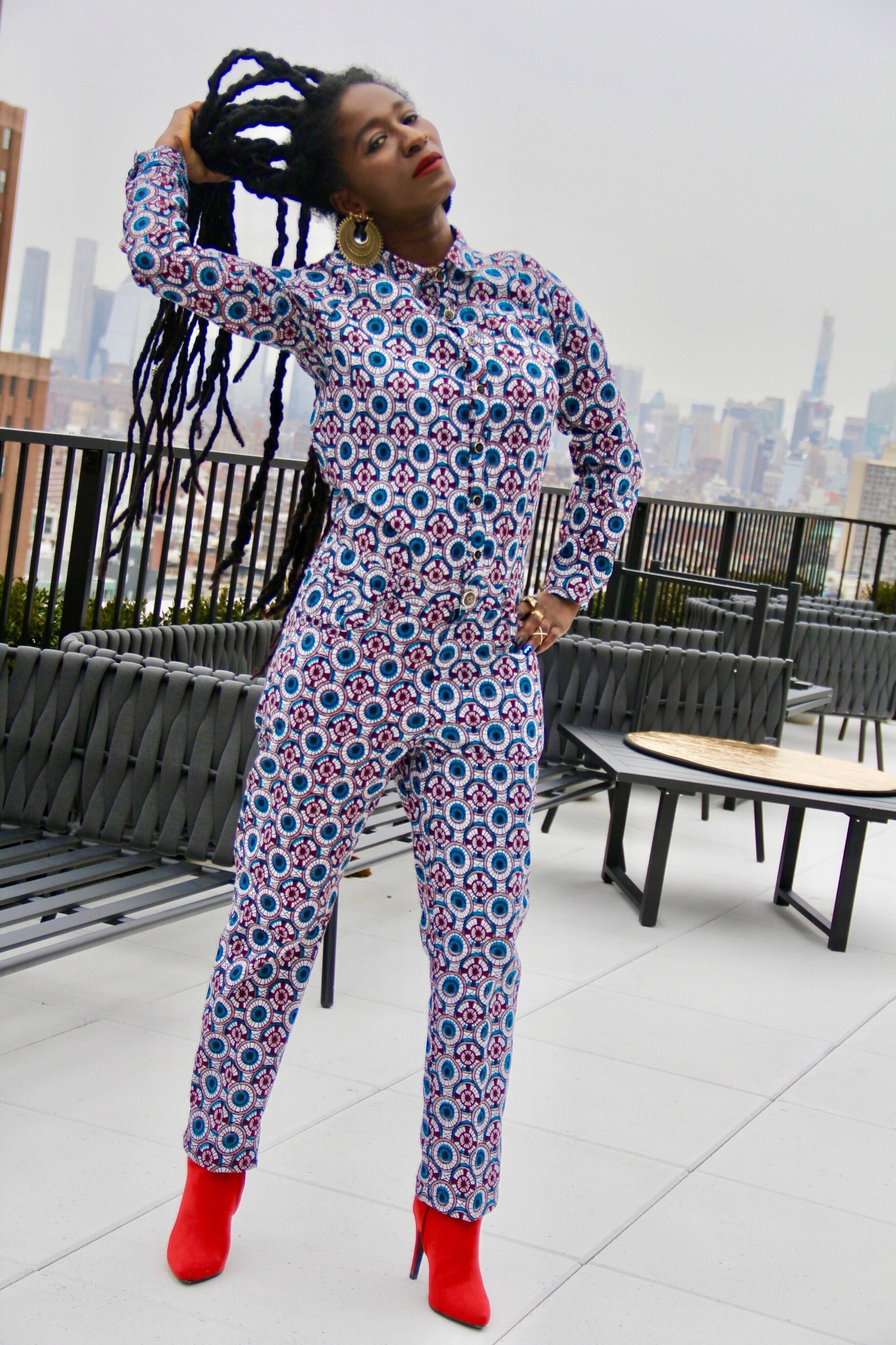 Model wearing the jumpsuit with blue, red, and white circle and square pattern that looks like a kaleidoscope