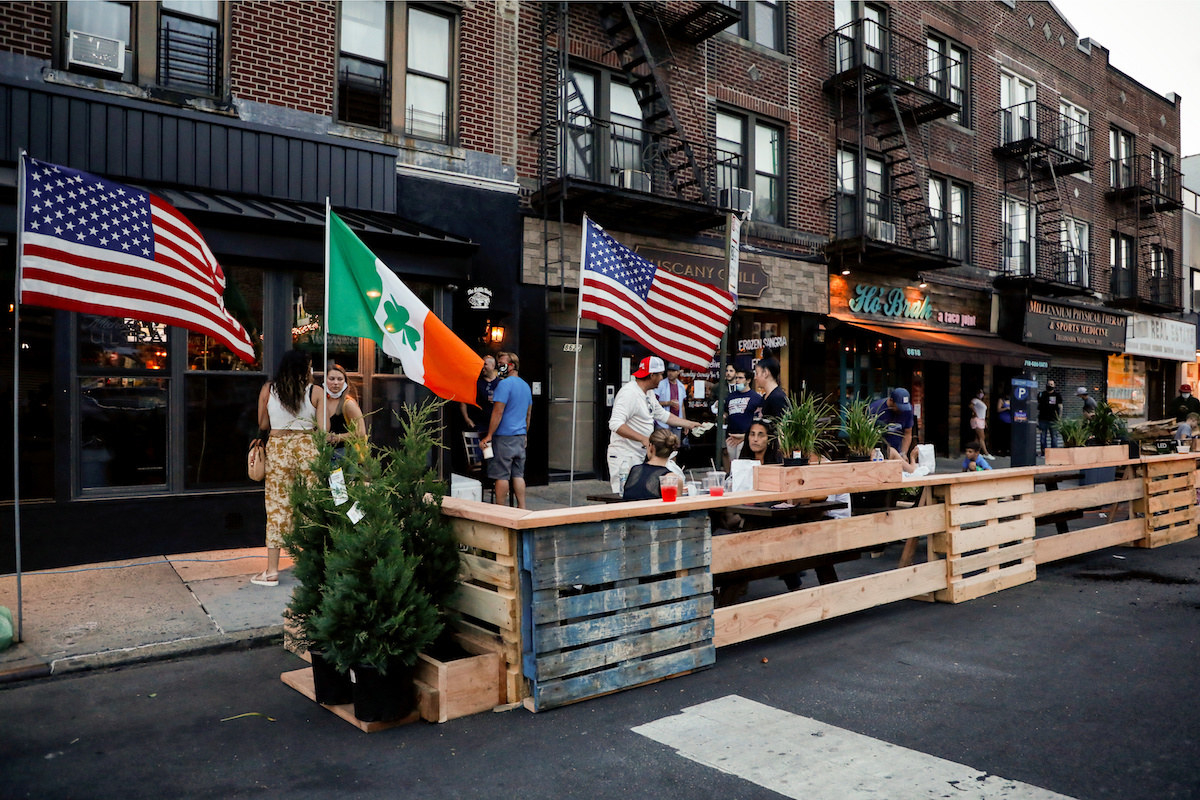 People dine in parking spaces on the street outside restaurants