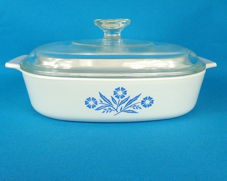 A white casserole dish with blue daisies drawn on it