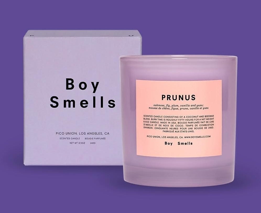 Candle in purple holder with the title &quot;Prunus&quot; and smell notes on it with a box next to it with the word &quot;Boy Smells&quot; on it