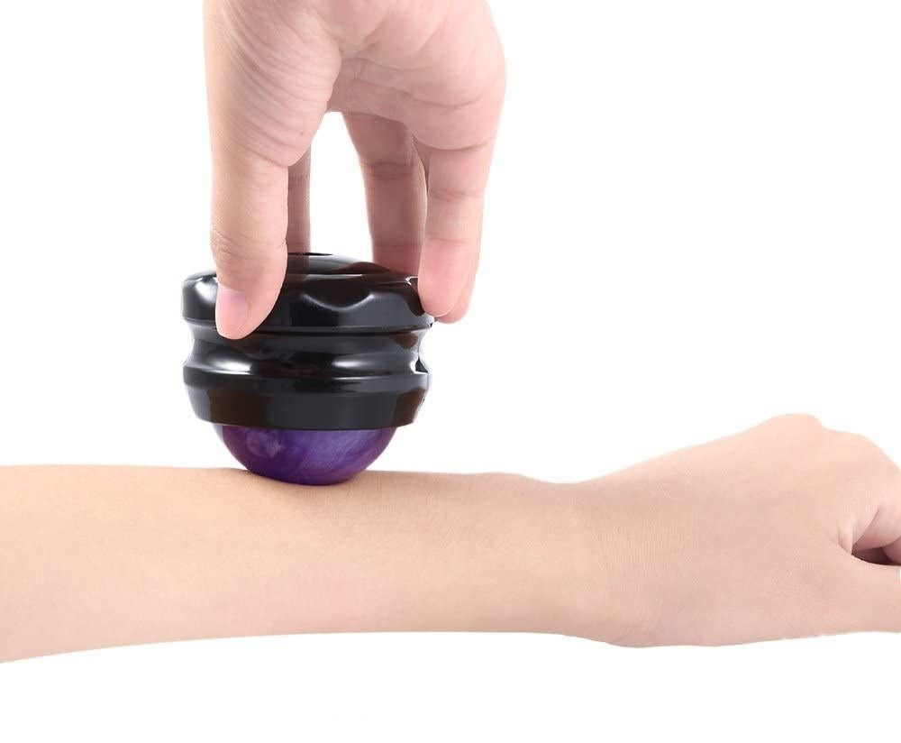 A person holding the grip cap on the massage ball and rolling it across their arm