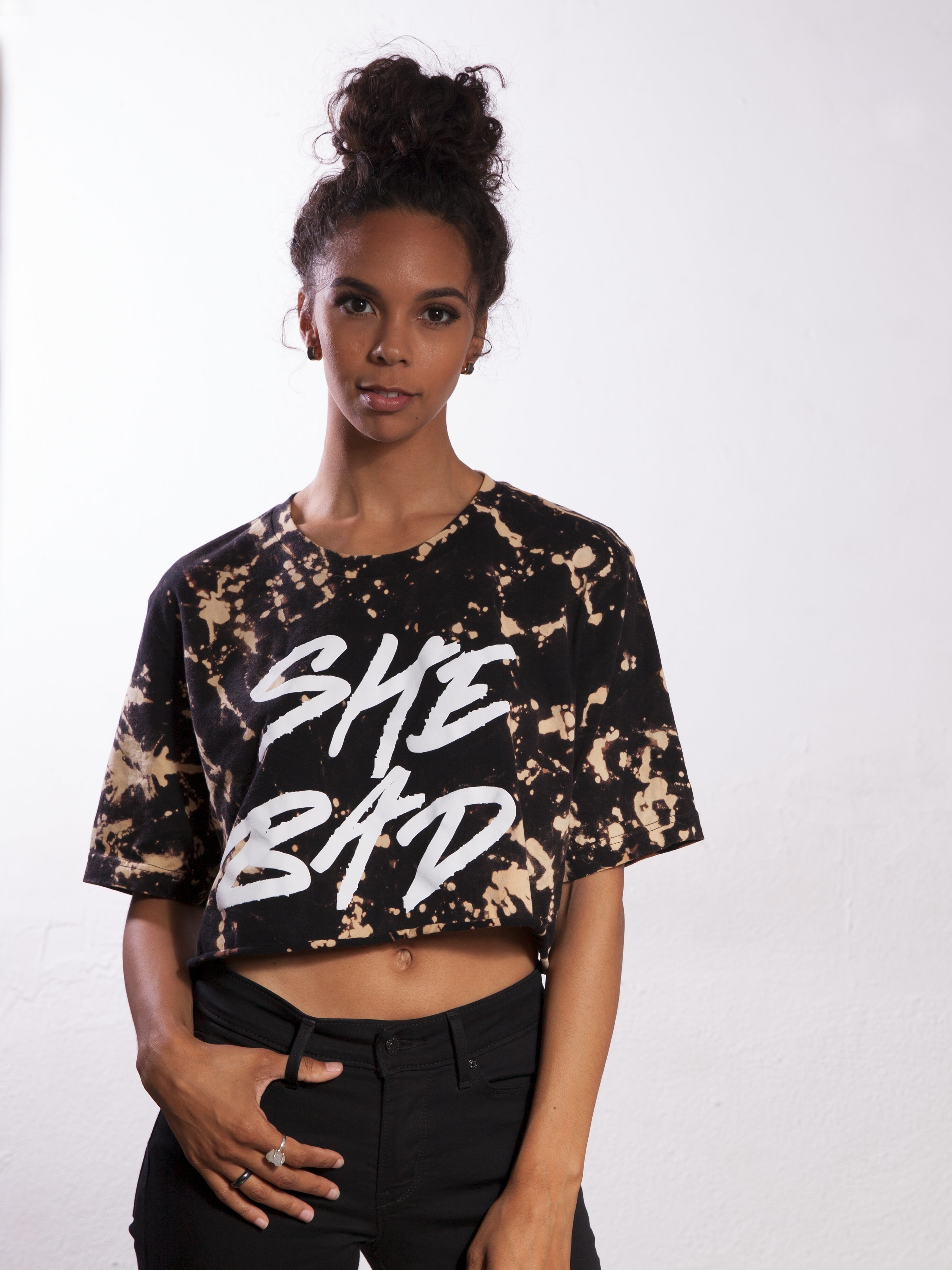 Model wearing the black bleach-dyed crop top with the phrase &quot;She Bad&quot; writing in big white letters on the front