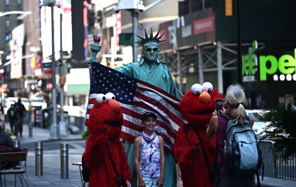 A girl poses with people dressed as the Statue of Liberty and Elmo in Times Square